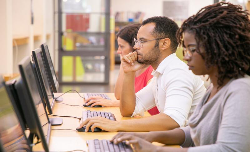 estudiantes en biblioteca usando computadoras